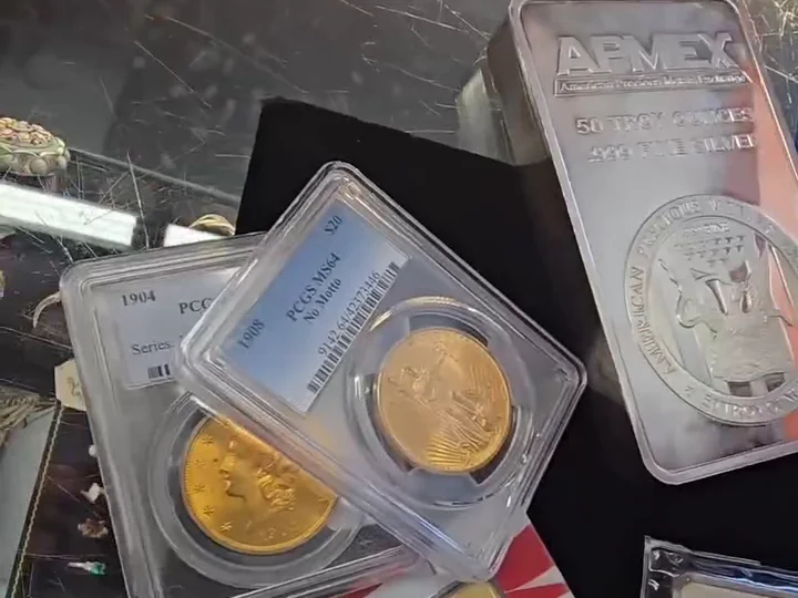 Graded gold coins and a silver bullion bar in the shop&rsquo;s display case